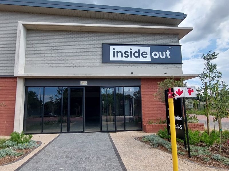 Front facade of a modern retail unit featuring brickwork, large glass entrance doors, and prominent signage.
