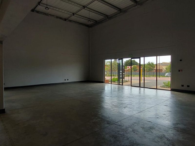 Spacious open-plan retail unit featuring polished concrete flooring, high ceilings, and large glass sliding doors providing ample natural light and street access.