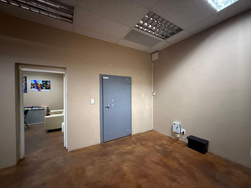 An industrial office space featuring a secure vault door, suspended ceiling with integrated lighting, and durable concrete flooring.