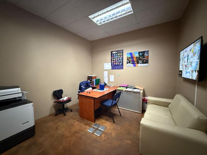 A functional industrial office space featuring a suspended ceiling, fluorescent lighting, and durable concrete flooring, suitable for administrative or operational use.