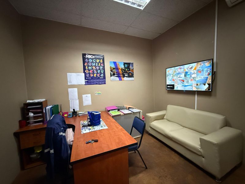 A functional office space featuring a suspended ceiling, recessed lighting, and a wall-mounted security monitoring system.