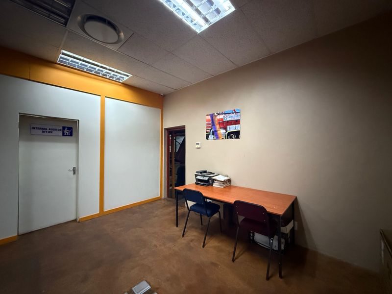 A functional office space featuring concrete flooring, suspended ceiling with recessed lighting, and a designated internal office entrance.