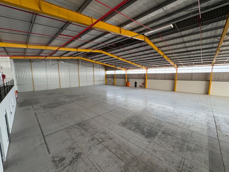 Spacious industrial warehouse featuring a high-clearance steel portal frame, concrete flooring, and an integrated fire sprinkler system.