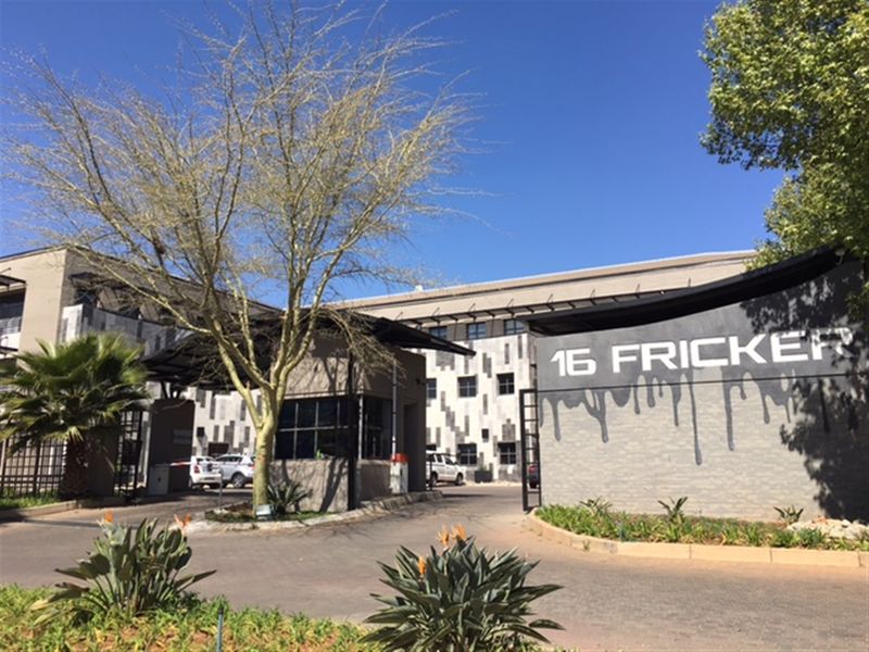 Front entrance view of the office property featuring a security gatehouse, boom gate access, and prominent building signage.