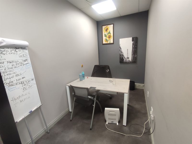 A compact, functional office space featuring neutral grey walls, recessed ceiling lighting, and integrated electrical and data connectivity points.