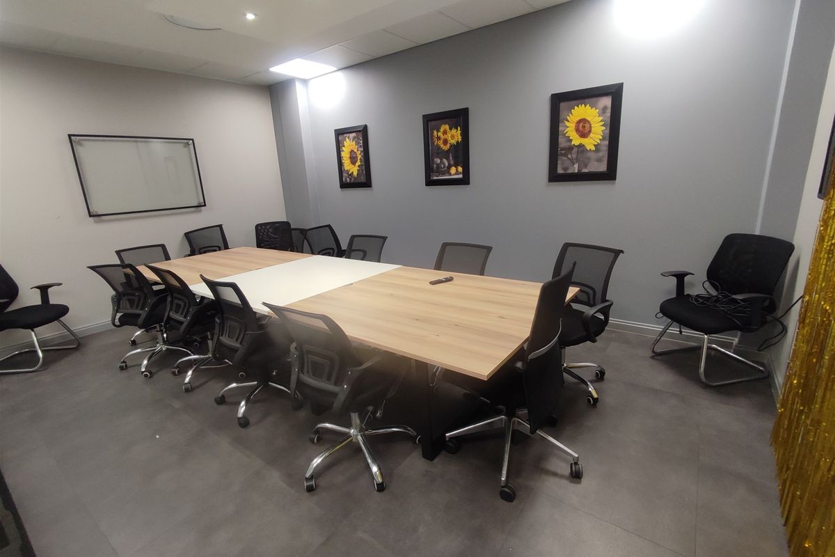 A professional office meeting room featuring tiled flooring, recessed ceiling lighting, and a wall-mounted whiteboard.