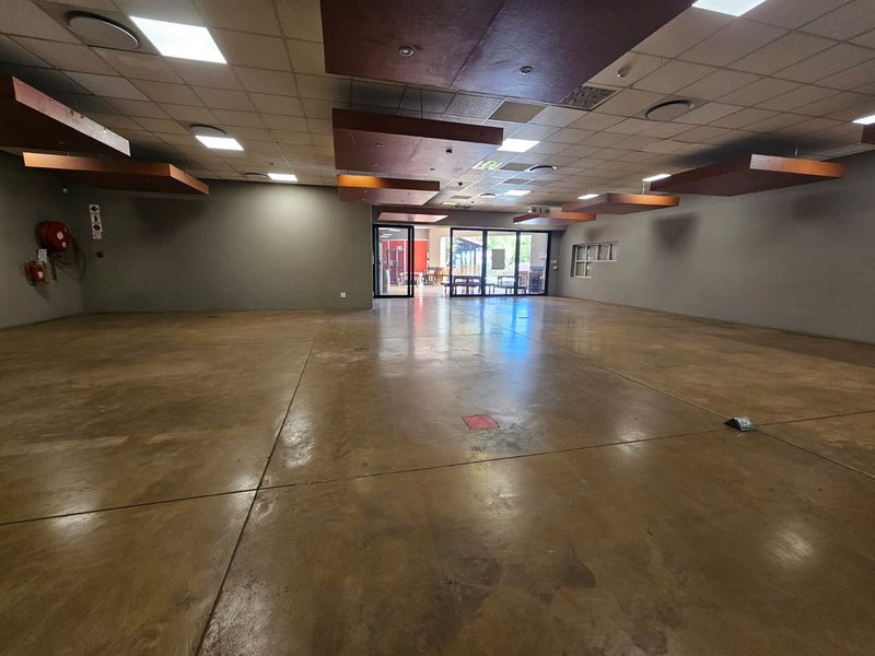 Spacious open-plan retail area featuring polished concrete flooring, suspended ceiling panels, and recessed lighting, offering a versatile layout for various business applications.