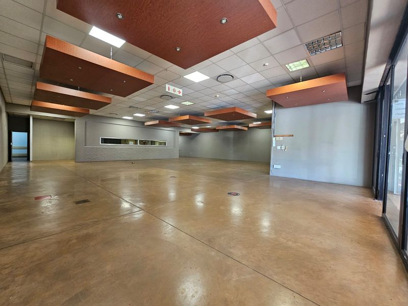 Spacious open-plan retail area featuring polished concrete floors, a suspended ceiling with decorative bulkheads, and a large glass storefront for high visibility.
