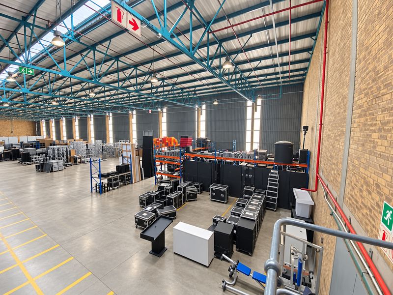 Spacious industrial warehouse featuring high ceilings with exposed steel trusses, concrete flooring, and functional fire safety infrastructure.
