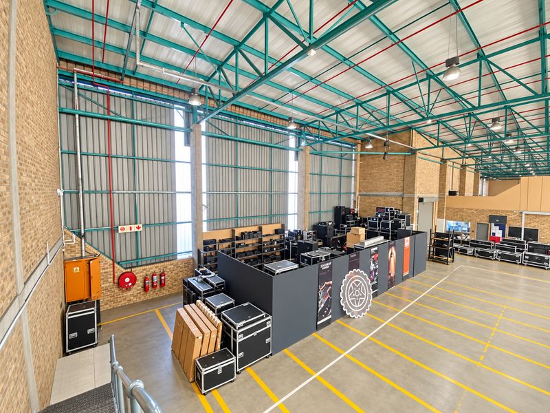 Spacious industrial warehouse facility featuring high ceilings with exposed steel trusses, concrete flooring, and functional fire safety infrastructure.