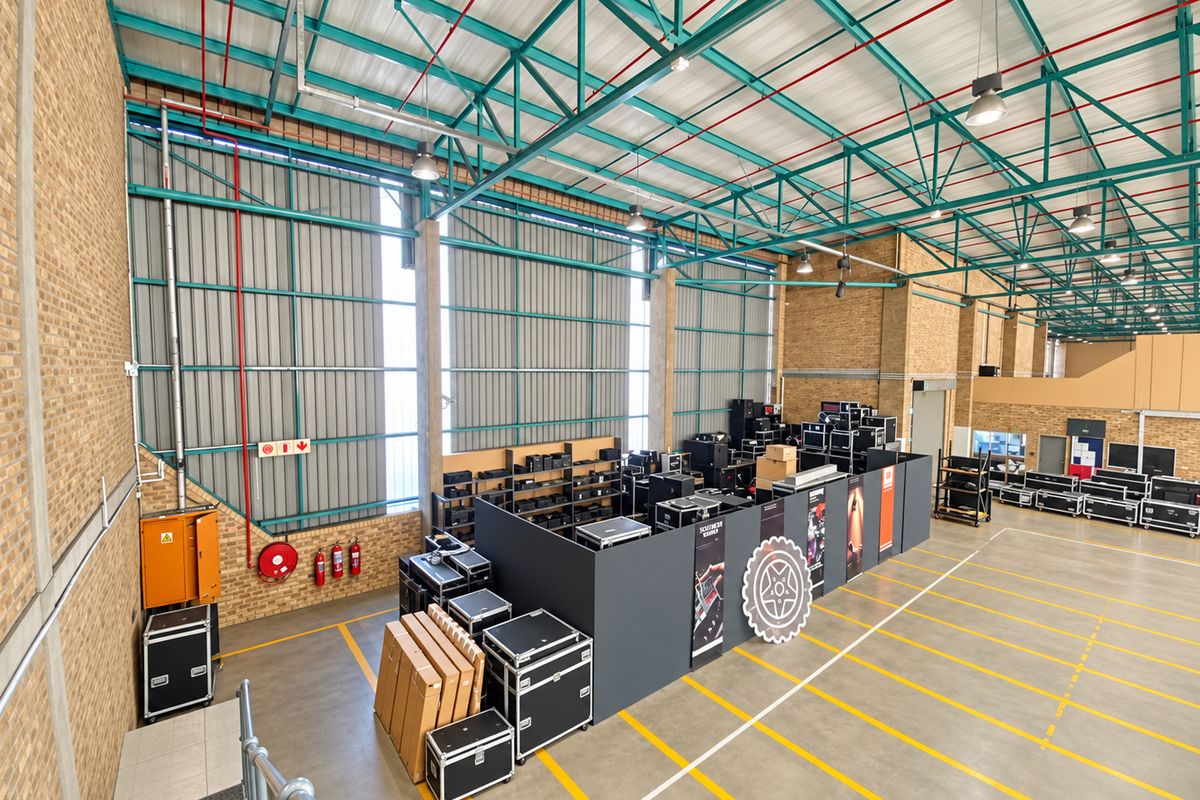 Spacious industrial warehouse facility featuring high ceilings with exposed steel trusses, concrete flooring, and functional fire safety infrastructure.