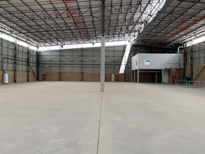 Spacious industrial warehouse featuring high ceilings with exposed steel trusses, concrete flooring, integrated sprinkler system, and a mezzanine level for versatile operational use.