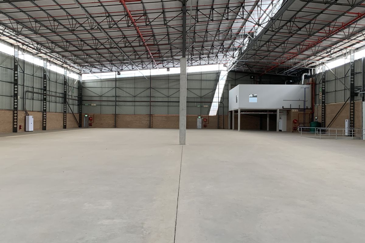 Spacious industrial warehouse featuring high ceilings with exposed steel trusses, concrete flooring, integrated sprinkler system, and a mezzanine level for versatile operational use.