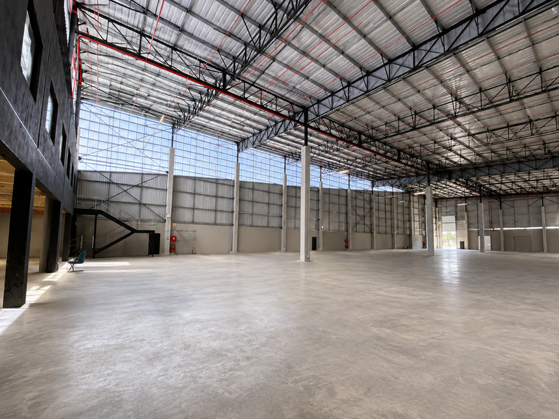 Expansive industrial warehouse space featuring high ceilings with exposed steel trusses, polished concrete flooring, and integrated fire safety systems.