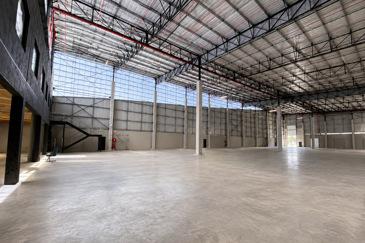 Expansive industrial warehouse space featuring high ceilings with exposed steel trusses, polished concrete flooring, and integrated fire safety systems.