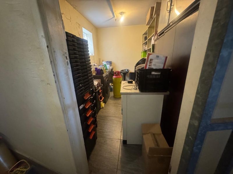 A small utility or storage space featuring tiled flooring and basic wall shelving, currently used for general storage.