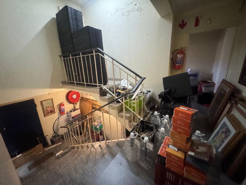 Interior staircase area featuring metal railings and fire safety equipment, showing signs of significant wear and maintenance requirements.