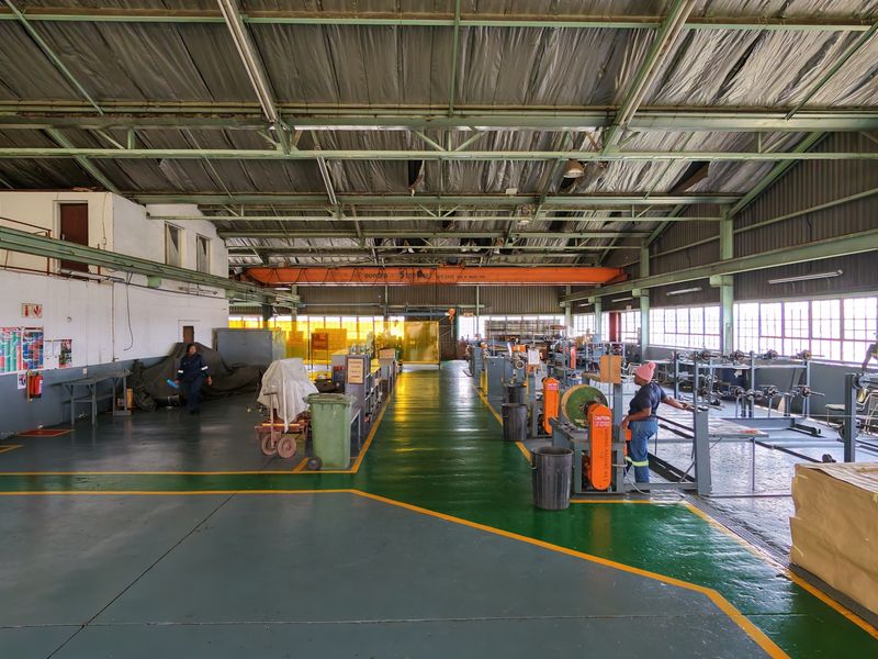 Spacious industrial warehouse facility featuring high ceilings with an overhead gantry crane, large windows for natural light, and durable painted concrete flooring.