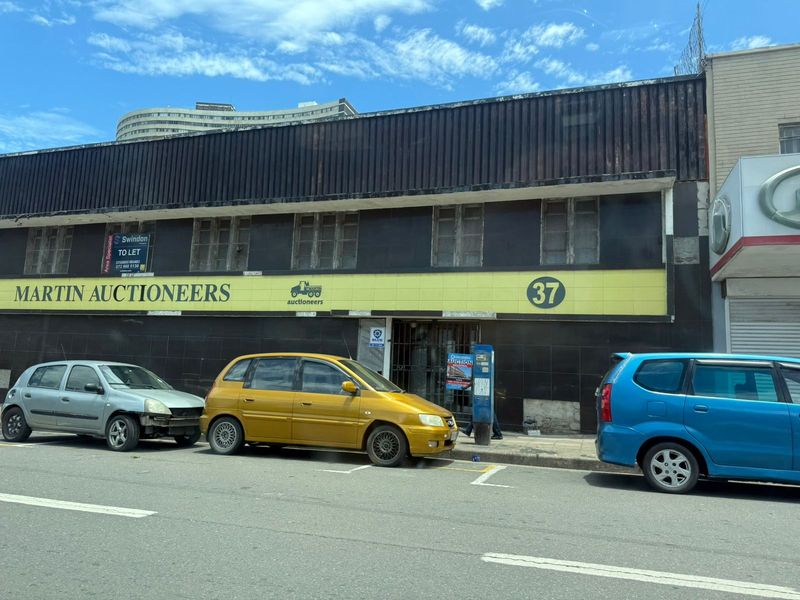 Street-level view of a commercial industrial building featuring a prominent facade with signage, metal cladding, and ground-floor access.