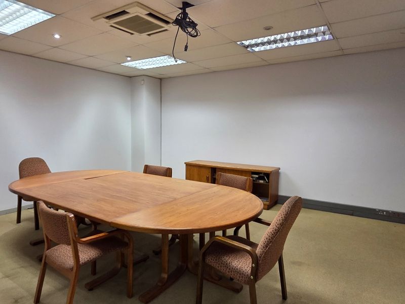 A functional office meeting room featuring a suspended ceiling with integrated lighting, air conditioning, and carpeted flooring.