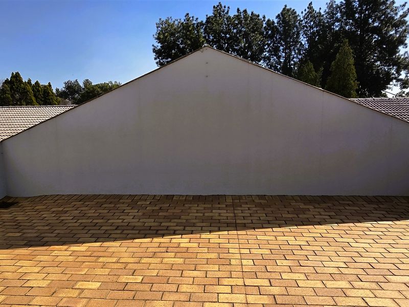 An open-air paved balcony or terrace area featuring surrounding parapet walls and views of the adjacent tiled roof structure.