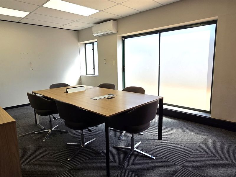 A professional office space featuring a suspended ceiling, recessed lighting, split-system air conditioning, and large windows providing ample natural light.