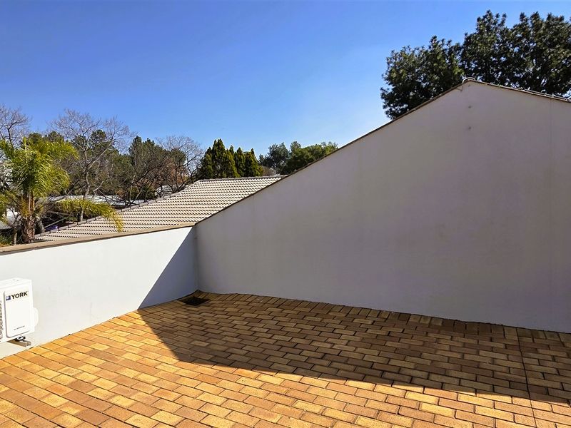 An open-air balcony featuring paved flooring, a perimeter wall, and installed air conditioning condenser units.