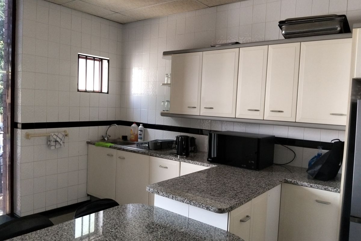 Functional industrial kitchen area featuring granite countertops, ample built-in cabinetry, and tiled wall finishes.