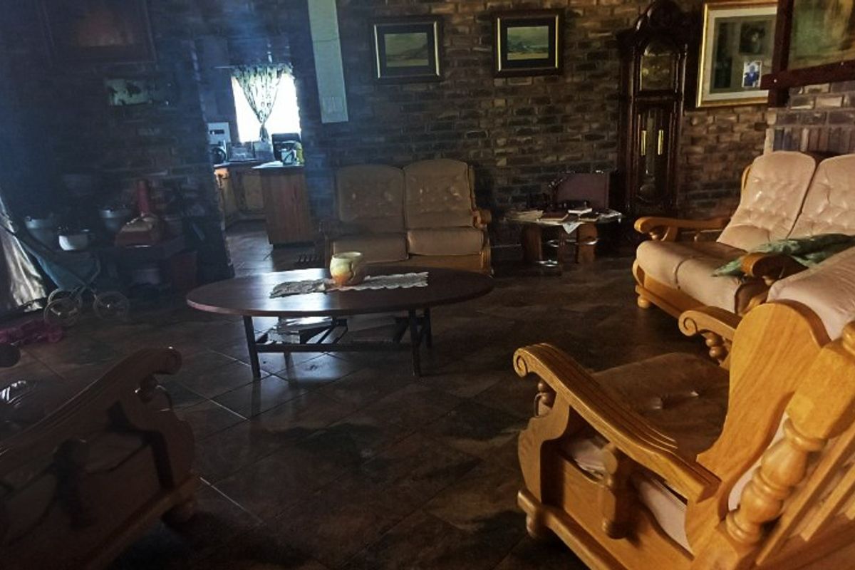 A rustic living room featuring exposed brick walls, tiled flooring, and a sliding glass door leading to the exterior.