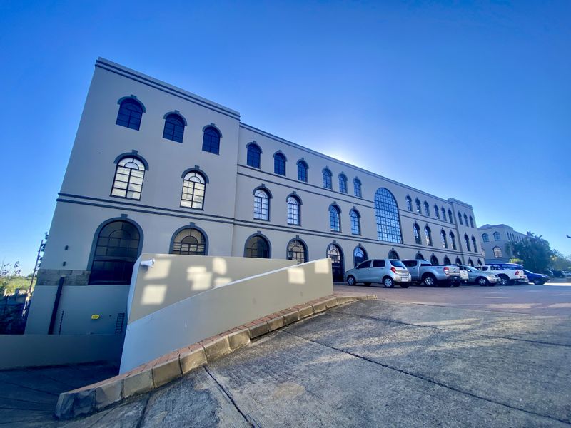 A wide-angle view of the industrial property's front facade, featuring arched windows, a concrete driveway, and a multi-story exterior structure.