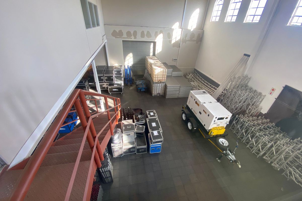 Spacious industrial utility area featuring high ceilings, arched windows, a metal staircase, and a large roller shutter door for easy access.