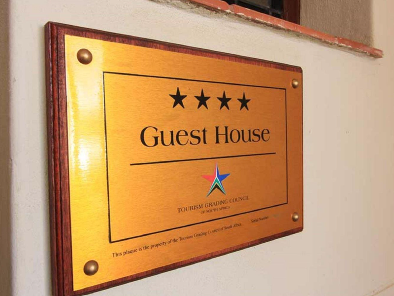 A four-star Tourism Grading Council of South Africa plaque mounted on an interior wall, indicating the official guest house rating.