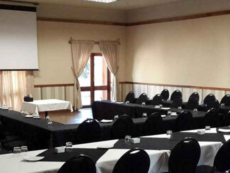 A functional conference or meeting room setup featuring a projector screen, neutral wall finishes, and direct access to an outdoor area.