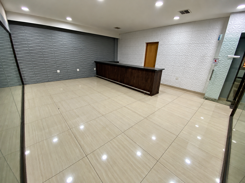 Modern office space featuring polished porcelain floor tiles, a built-in reception counter, and contemporary textured feature walls with recessed downlighting.