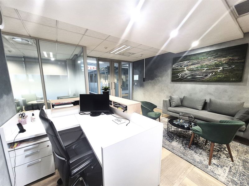 A modern office reception area featuring a built-in desk, glass partition walls, and contemporary finishes with a professional aesthetic.