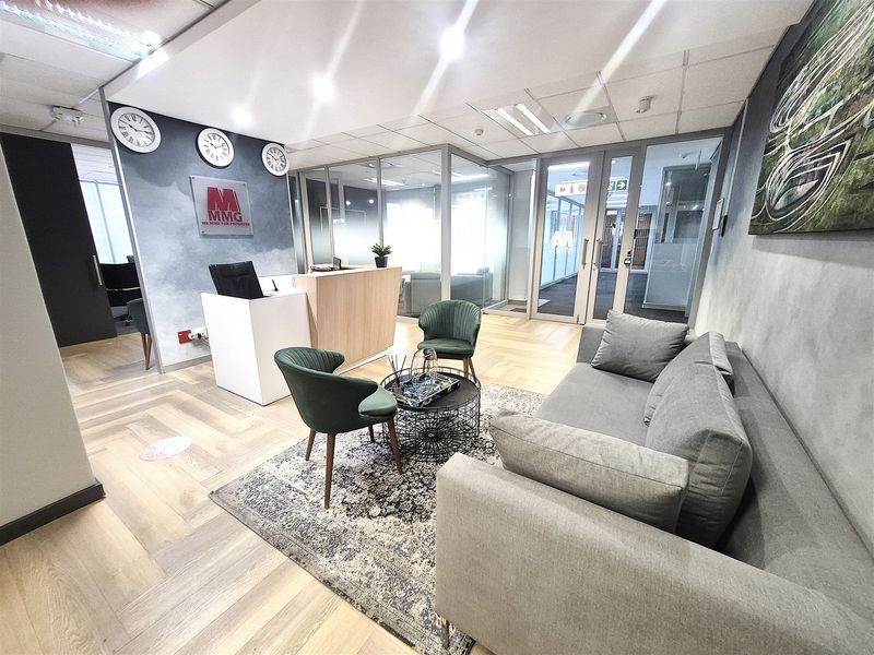 Modern office reception area featuring a professional reception desk, glass partitioning for private offices, and high-quality herringbone wood flooring.