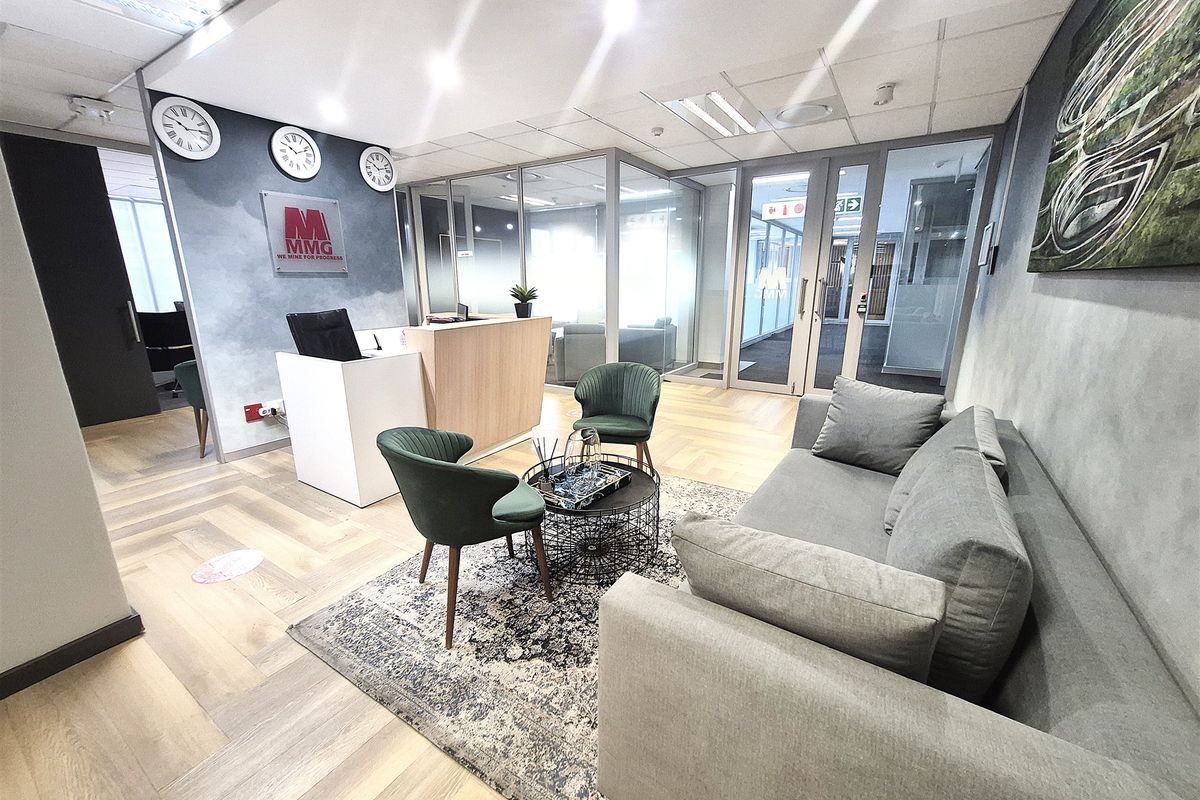 Modern office reception area featuring a professional reception desk, glass partitioning for private offices, and high-quality herringbone wood flooring.