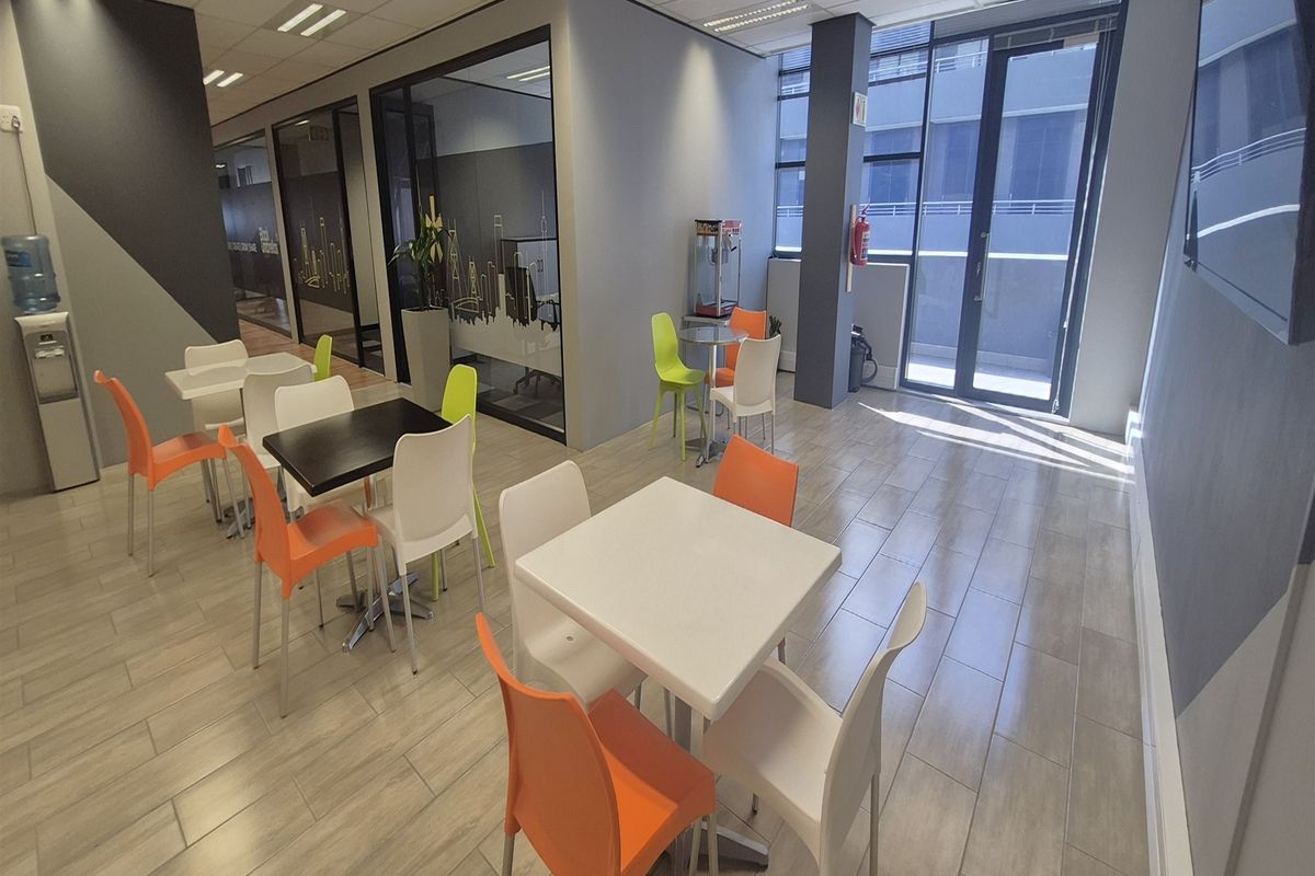 Modern office break-out area featuring tiled flooring, suspended ceilings, and glass partition walls, providing a bright and professional workspace environment.
