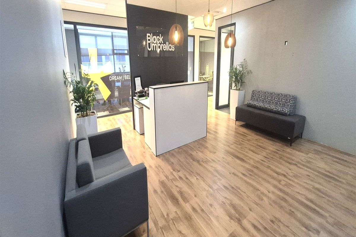 Modern office reception area featuring laminate flooring, glass partitions, and contemporary pendant lighting, creating a professional and welcoming entrance for clients.