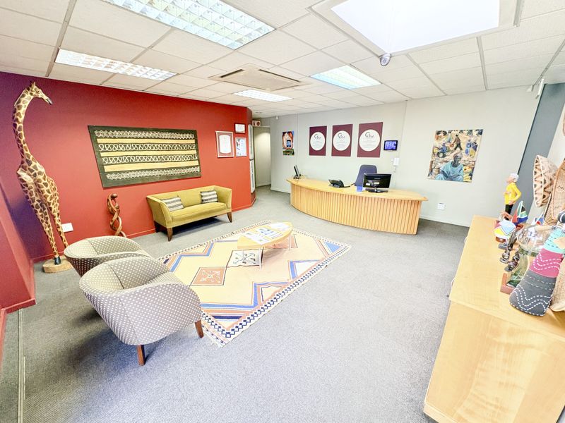 A professional office reception area featuring a curved built-in reception desk, suspended ceiling with recessed lighting, and integrated air conditioning.