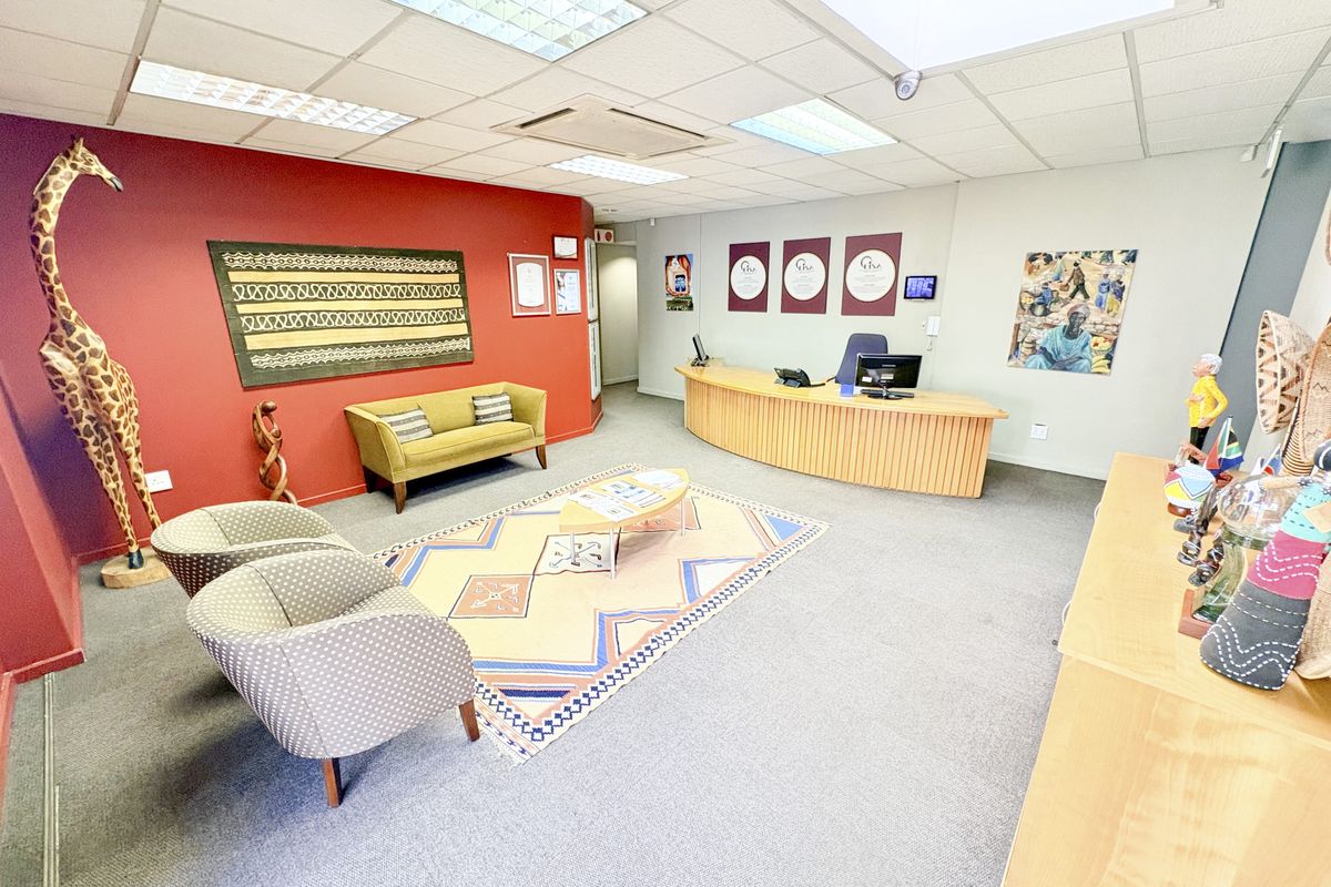 A professional office reception area featuring a curved built-in reception desk, suspended ceiling with recessed lighting, and integrated air conditioning.