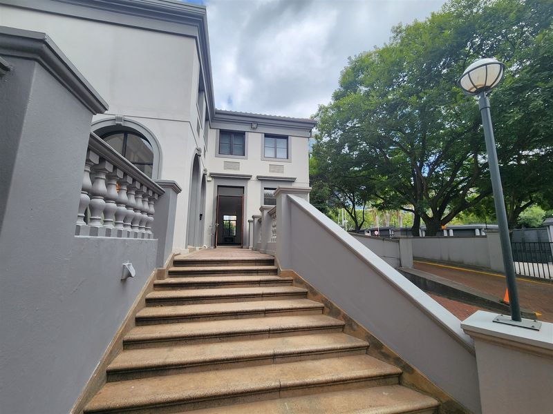 A well-maintained office building entrance featuring a stone staircase, elegant balustrades, and a prominent arched doorway.
