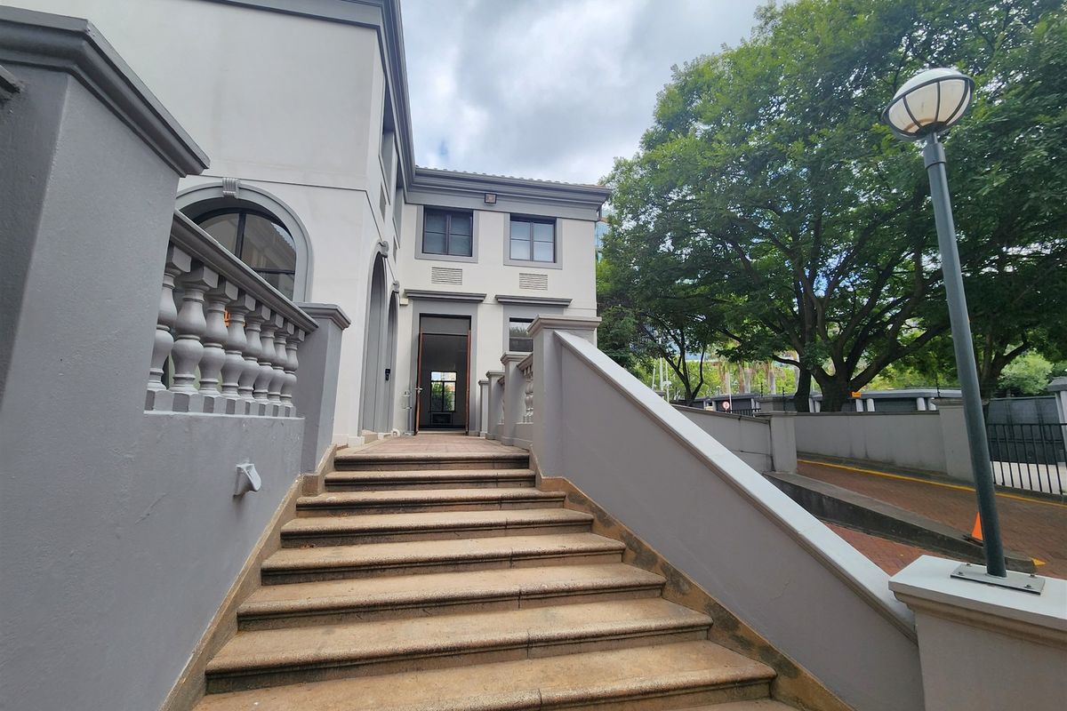 A well-maintained office building entrance featuring a stone staircase, elegant balustrades, and a prominent arched doorway.