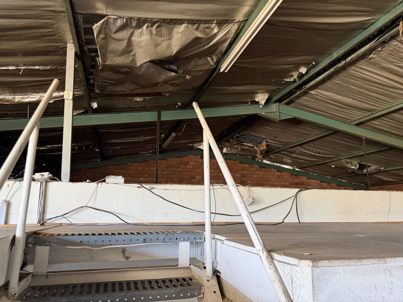 Industrial mezzanine level featuring exposed steel trusses and brickwork, currently showing significant wear and damage to the roof insulation and structural finishes.