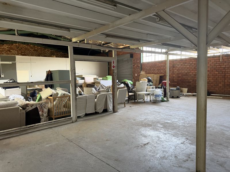 Spacious industrial utility area featuring exposed brick walls, steel structural beams, and concrete flooring, suitable for storage or workshop use.