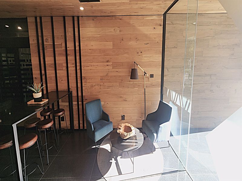 Modern office space featuring warm timber wall paneling, sleek glass partitioning, and contemporary tiled flooring, creating a professional and inviting work environment.