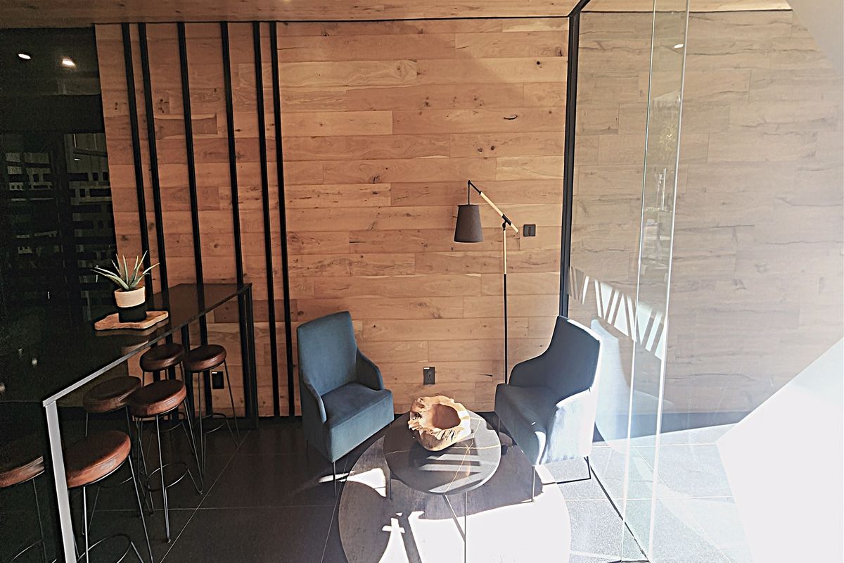 Modern office space featuring warm timber wall paneling, sleek glass partitioning, and contemporary tiled flooring, creating a professional and inviting work environment.