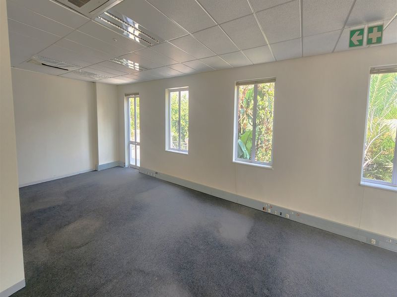 A vacant office space featuring a suspended ceiling, recessed lighting, carpeted flooring, and perimeter trunking for electrical and data connectivity.