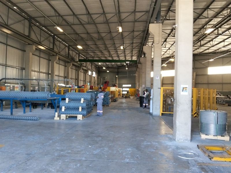 Spacious industrial warehouse facility featuring high ceilings, exposed steel truss roofing, concrete flooring, and robust support columns suitable for manufacturing or storage operations.
