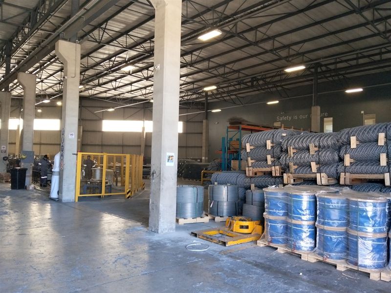 Spacious industrial warehouse facility featuring high ceilings with exposed steel trusses, concrete columns, and durable polished concrete flooring.